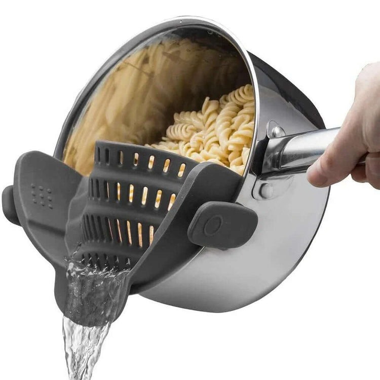 Clip On Silicone Pot Strainer draining cooked pasta from a pot with a hand holding the strainer.