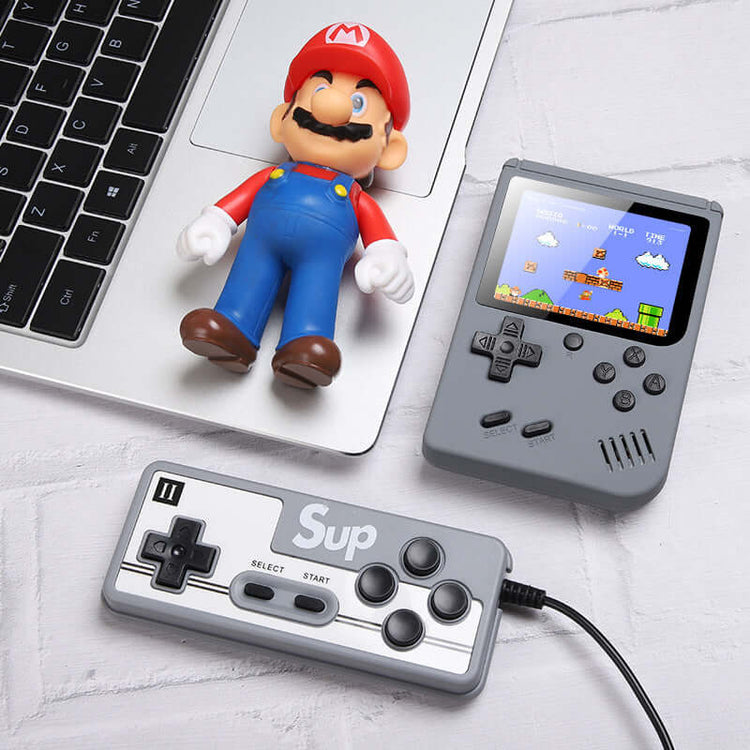 Retro Mini Handheld Game Console with controller and retro figure on a laptop