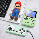 Retro Mini Handheld Game Console next to a laptop and figurine on a table.
