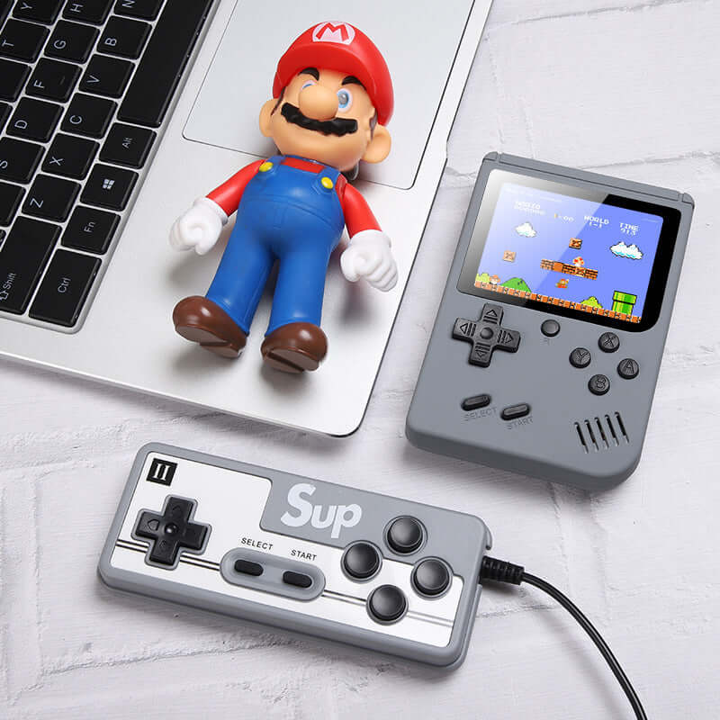 Retro Mini Handheld Game Console with controller and retro figure on a laptop