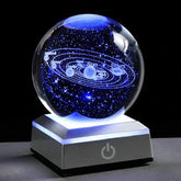 3D Crystal Galaxy Ball illuminated, displaying a mini-universe with stars and planets on a desk.