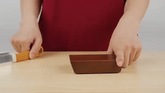 Hands demonstrating the Rolling Knife Sharpener with a knife and sharpening tray on a wooden surface.