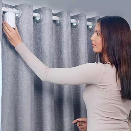 Woman installing Smart Curtain Robot on gray curtains for automated control