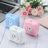 Colorful PeriPage Pocket Printers in blue, white, and pink next to a laptop with flowers in the background, showcasing the compact design.